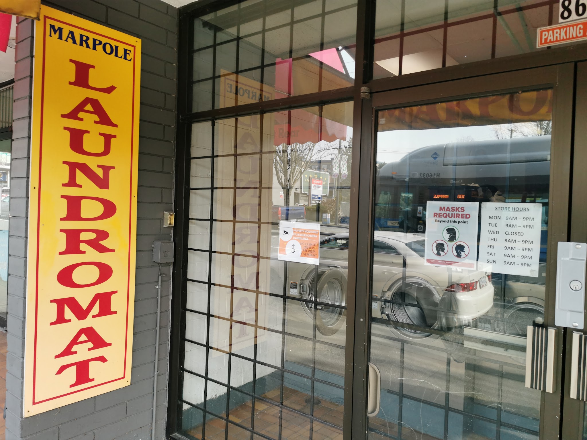 Marpole Laundromat entrance with yellow vertical sign and glass door