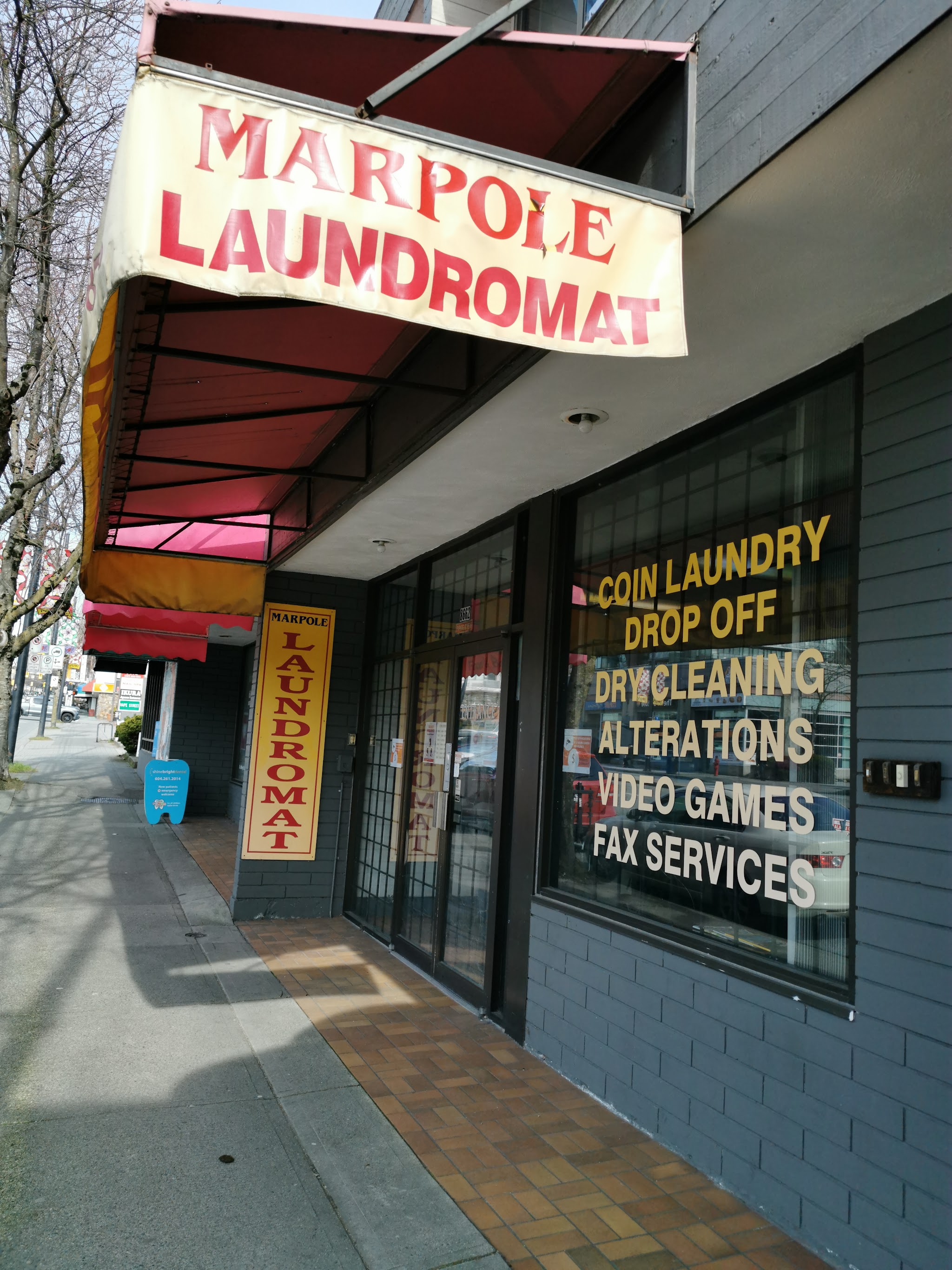 Marpole Laundromat full storefront exterior with red awning and services listed on window